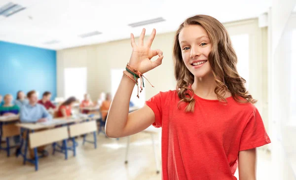 Sonriente adolescente estudiante mostrando ok en la escuela —  Fotos de Stock