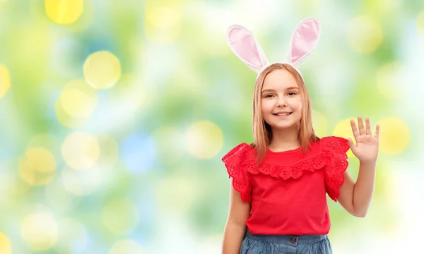 Щаслива дівчина в великодніх вухах кролика махає рукою — стокове фото