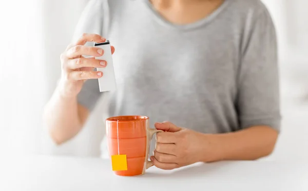 Close up of woman adding sweetener to cup of tea — Stock Photo, Image
