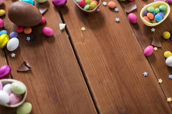 Ovos de chocolate e gotas de doces na mesa de madeira — Fotografia de Stock