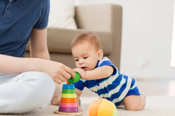 Мальчик с отцом и пирамидой игрушки дома — стоковое фото