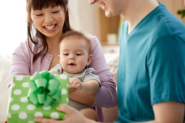 Familia feliz con bebé hijo y regalo en casa — Foto de Stock