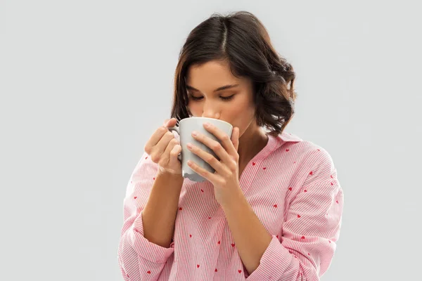 Mladá žena v pyžamě pije kávu z džbánu — Stock fotografie