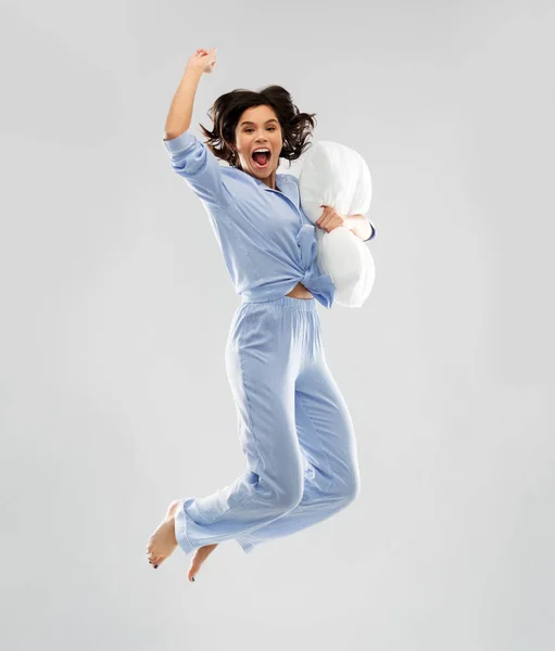 Щаслива жінка в блакитній піжамі стрибає з подушкою — стокове фото