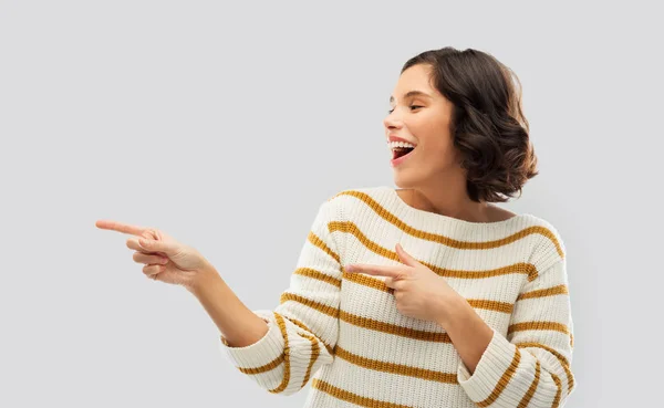 Glücklich lächelnde Frau zeigt mit dem Finger auf etwas — Stockfoto