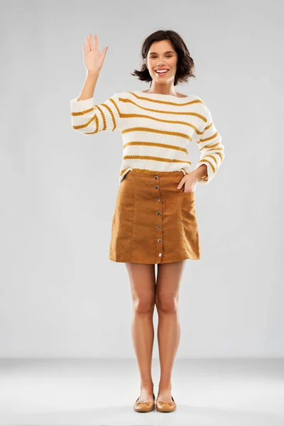 Žena v pulovenci, sukně a obuv mávající ruku — Stock fotografie