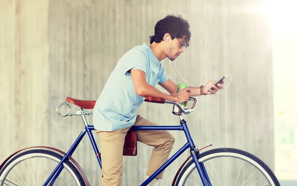 Muž s smartphone a sluchátka na kole — Stock fotografie
