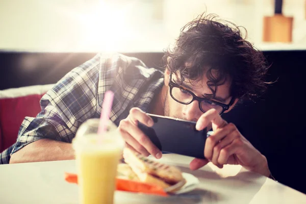 Homem com smartphone fotografar alimentos no café — Fotografia de Stock