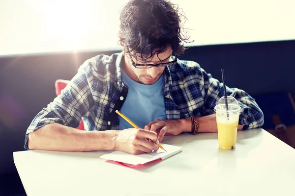 Hombre con cuaderno y jugo escribiendo en la cafetería —  Fotos de Stock