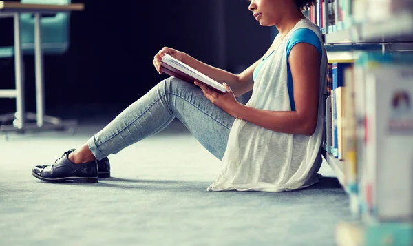 Happy african student girl reading book at library — Stock Photo, Image