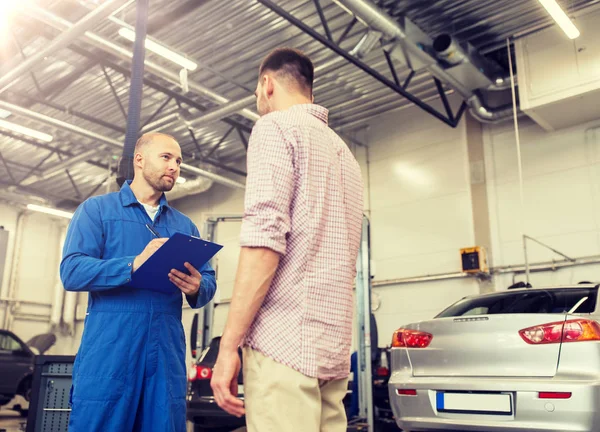 Auto mekaniker med Urklipp och man på bilverkstad — Stockfoto