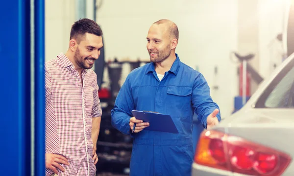 Automechaniker mit Klemmbrett und Mann im Autohaus — Stockfoto
