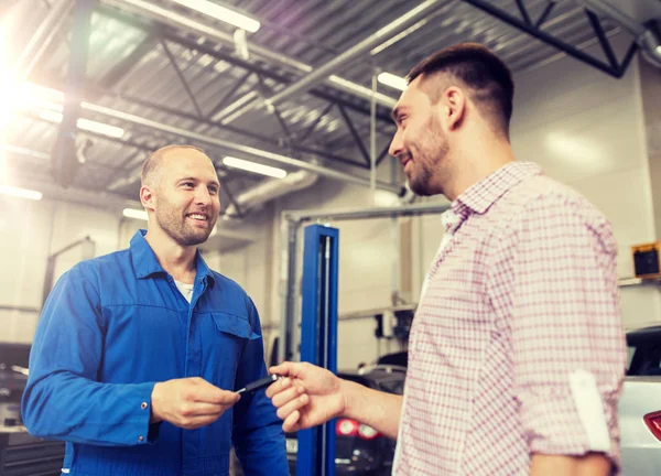 Bilmekaniker som ger nyckeln till mannen på bil shop — Stockfoto