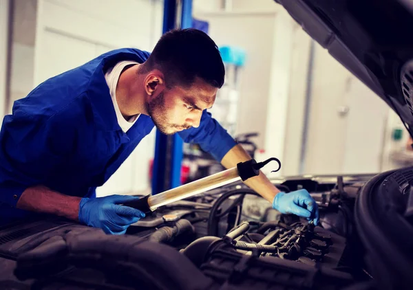 Monteur man met lamp repareren auto bij workshop — Stockfoto