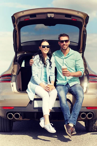 Happy couple with coffee at hatchback car trunk — Stock Photo, Image