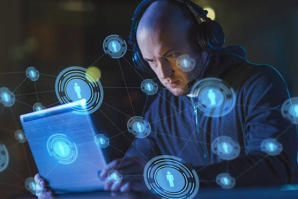 Hacker in headset typing on laptop in dark room — Stock Photo, Image