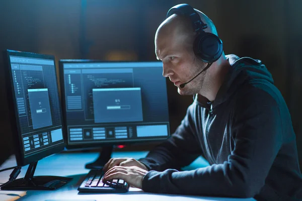 Hacker con ordenador y auriculares en habitación oscura — Foto de Stock