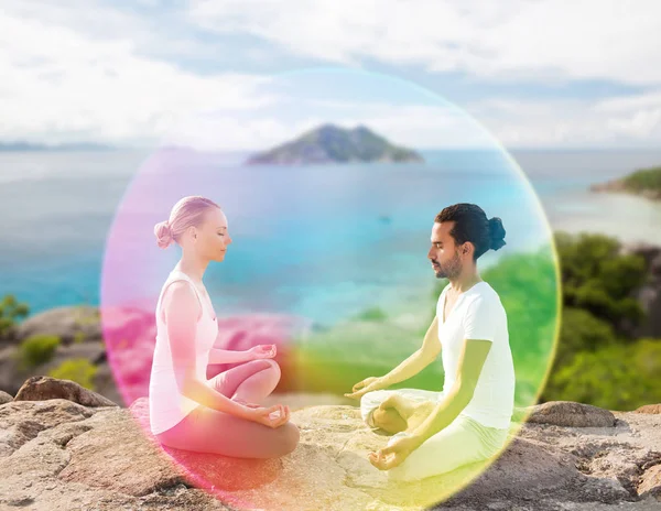 Pareja haciendo yoga en pose de loto con aura de arco iris —  Fotos de Stock