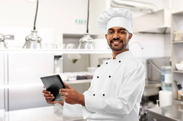 Индийский шеф-повар с планшетным ПК на кухне ресторана — стоковое фото