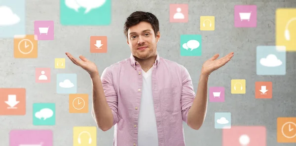 Jonge man schouderophalend over app iconen op Grey — Stockfoto