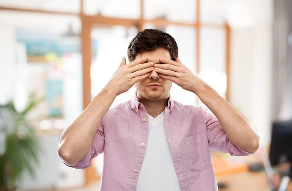 Homem fechando os olhos por mãos sobre sala de escritório — Fotografia de Stock