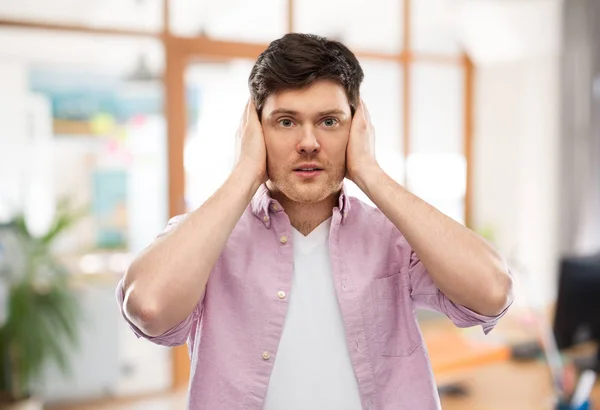 Man closing ears by hands over office room — Stock Photo, Image