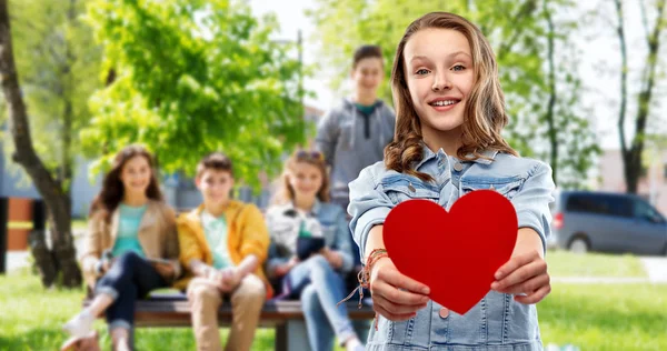 Lächelndes Teenager-Mädchen mit rotem Herz im Freien — Stockfoto