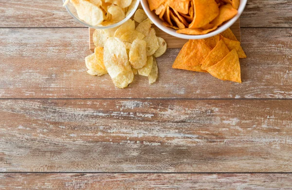 Close up of potato crisps and nachos in bowls — Stock Photo, Image