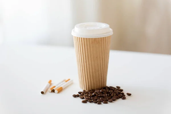 Close up of cigarettes, coffee cup and beans — Stock Photo, Image