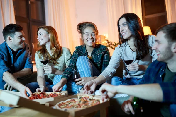 Amici mangiare pizza e bere vino rosso a casa — Foto Stock