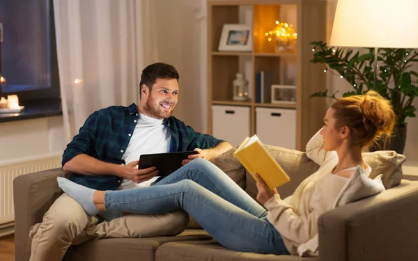 Casal com computador tablet e livro em casa — Fotografia de Stock