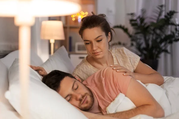 Kobieta budzi jej mąż śpi się w łóżku w domu — Zdjęcie stockowe