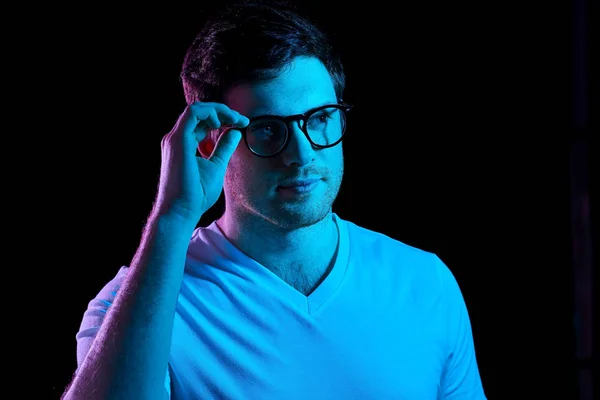 Hombre en gafas sobre luces de neón en habitación oscura —  Fotos de Stock