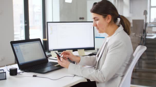 Programador trabaja con smartphone y portátil — Vídeo de stock