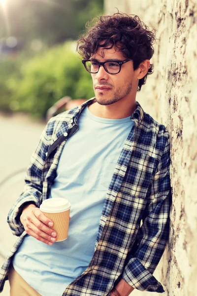 Homem em óculos bebendo café sobre parede de rua — Fotografia de Stock
