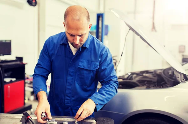 Mechaniker mit Schraubenschlüssel repariert Auto in Werkstatt — Stockfoto