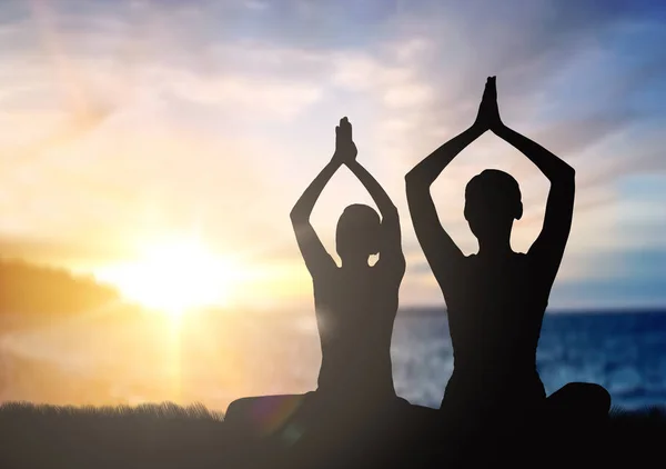 Couple doing yoga in lotus pose over sunset — Stock Photo, Image