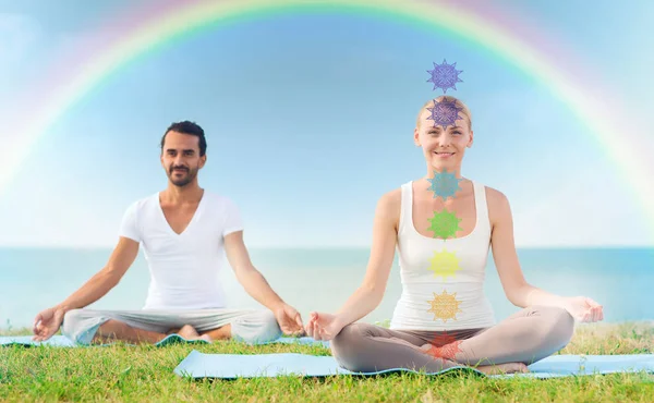 Coppia che fa yoga in posa loto con sette chakra — Foto Stock