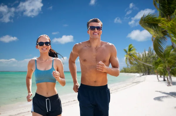 Para w ubraniach sportowych biegających wzdłuż plaży — Zdjęcie stockowe