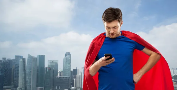 Muž na superhrdinském mysu používající smartphone přes město — Stock fotografie