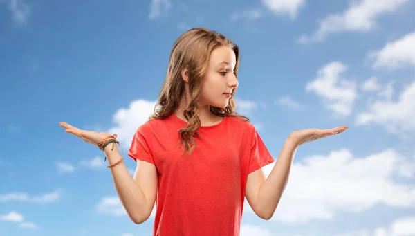 Smiling teenage girl holding empty hand over sky — Stock Photo, Image