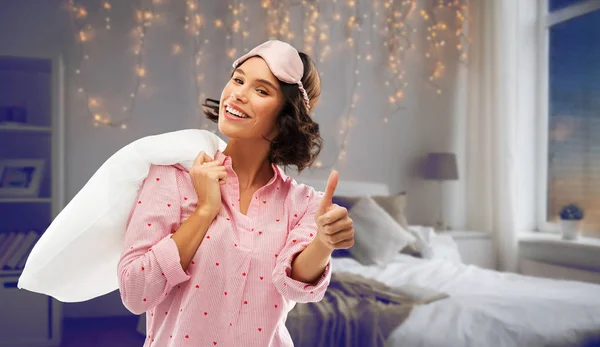 Vrouw met kussen in pyjama tonen thumbs up — Stockfoto