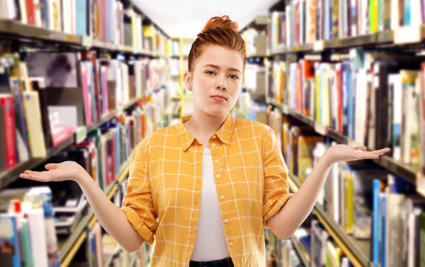 Triste fille étudiante rousse haussant les épaules à la bibliothèque — Photo