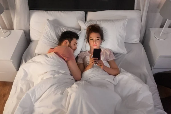 Mujer usando smartphone mientras su novio está durmiendo — Foto de Stock