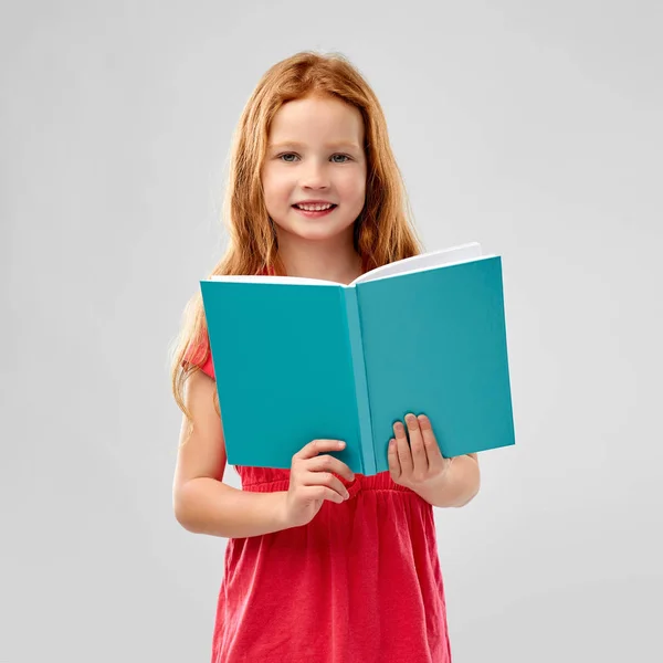 Czerwona dziewczyna czytania książki uśmiechem — Zdjęcie stockowe