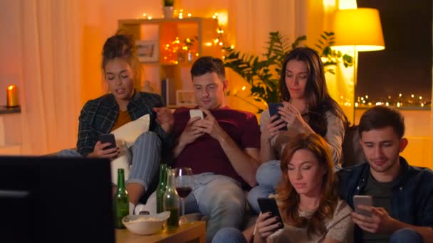 Amigos con smartphone viendo la televisión en casa — Vídeos de Stock