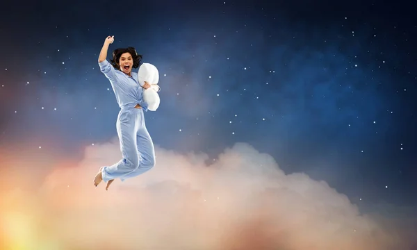 Glückliche Frau im blauen Pyjama springt mit Kissen — Stockfoto
