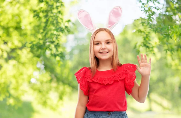 Щаслива дівчина в великодніх вухах кролика махає рукою — стокове фото