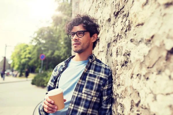 Man in eyeglasses drinking coffee over street wall — Stock Photo, Image