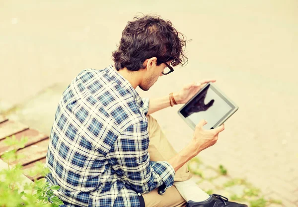 Muž s tablet pc sedí na lavičce ulice města — Stock fotografie